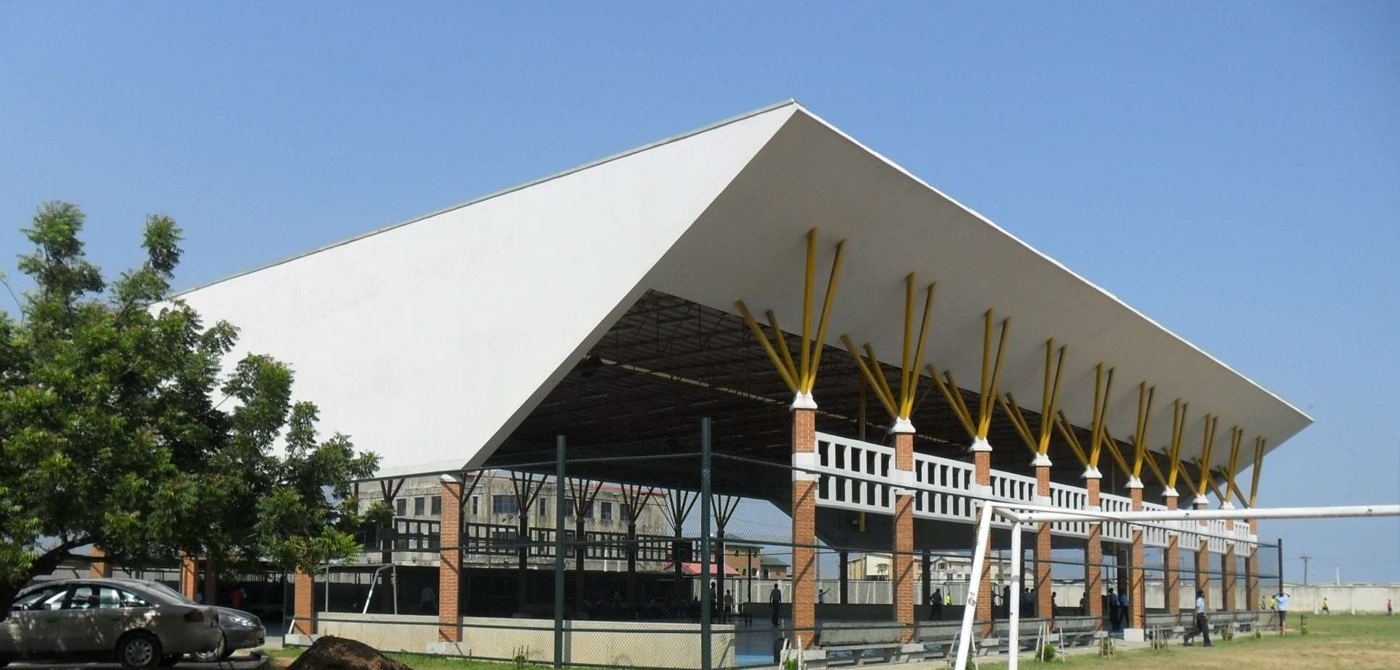 The covered sports court at Whitesands School, Lekki. A white folded roof on yellow struts, built by Donkem Construction for Ikota Educational Foundation.